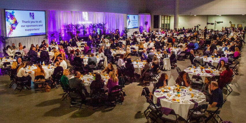 A room full of people sit at round tables