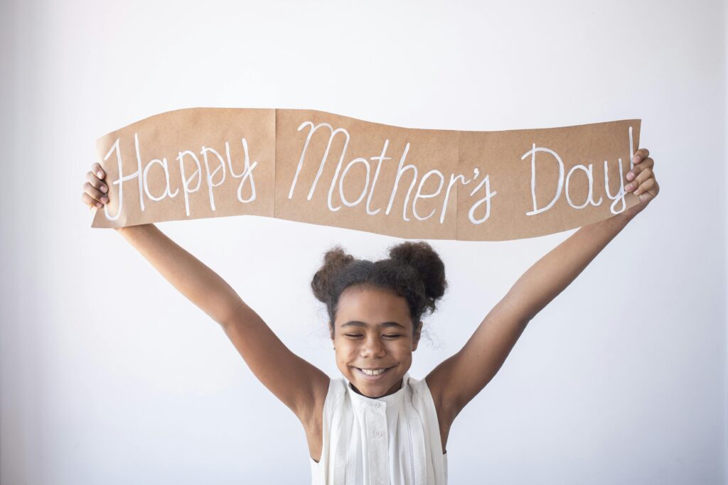 Young girl holds sign saying Happy Mother's Day