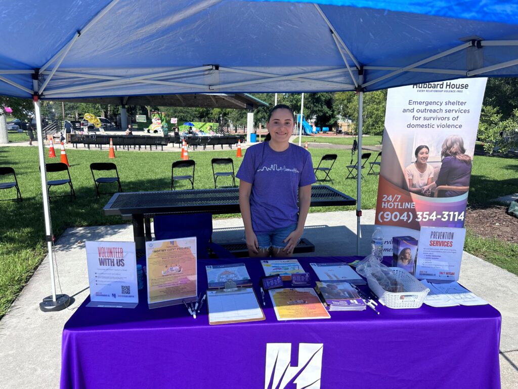 A woman stands behind a table covered in fliers