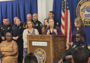 Several women stand at a podium with police officers behind them