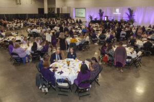 A ballroom of people sitting at round tables