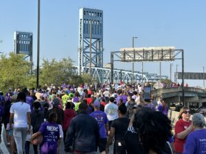 A large group of people walk toward a blue bridge