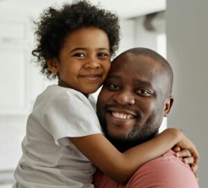 A man hugs his 10-year-old son and smiles